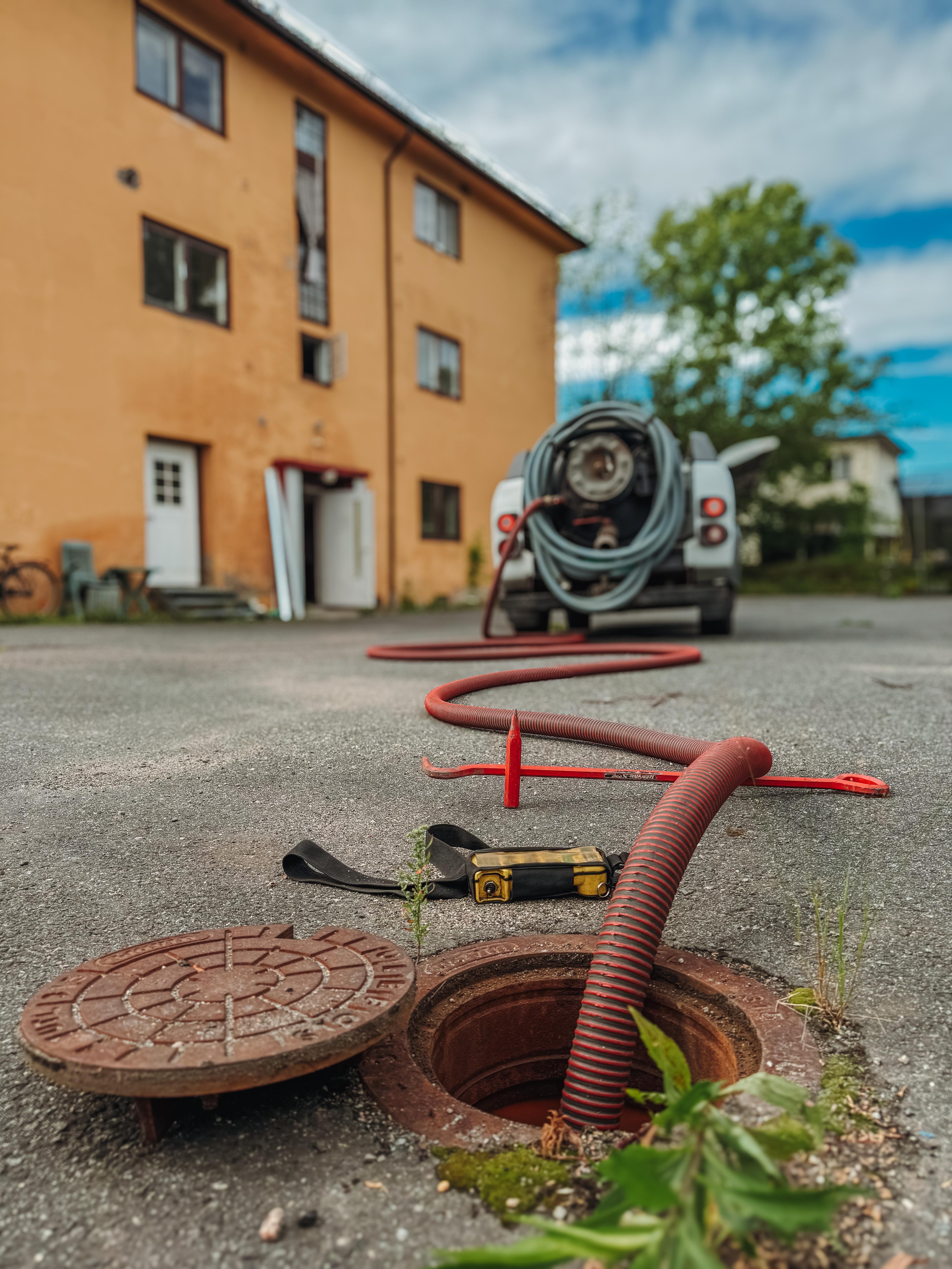 Bilde av sugebil parkert foran kum med sugeslangen ned i kummen