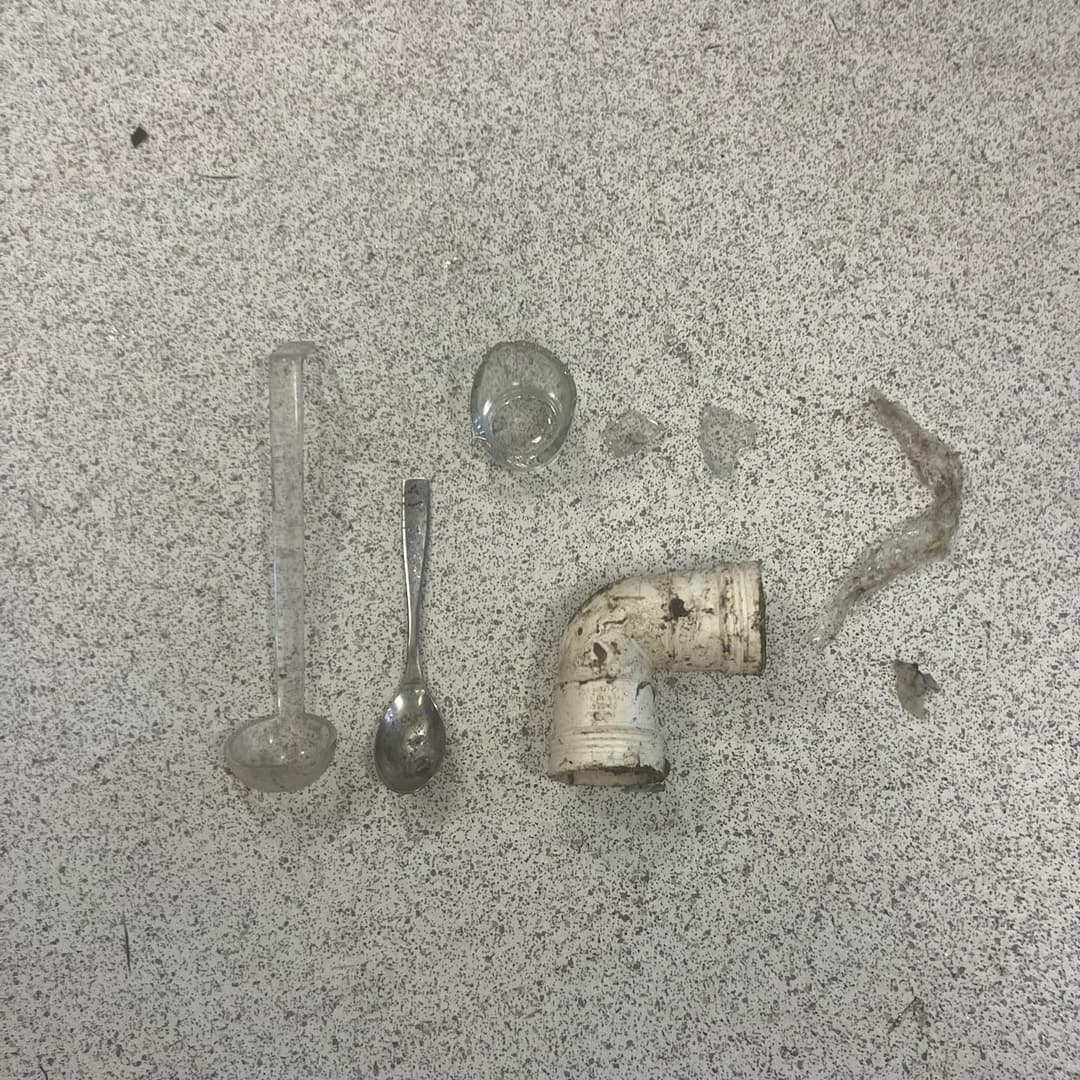 Resultatet etter at gripekloen har åpnet et tett avløp. Skje, øse, glassbiter og rørbiter hentet ut fra avløpsrøret.