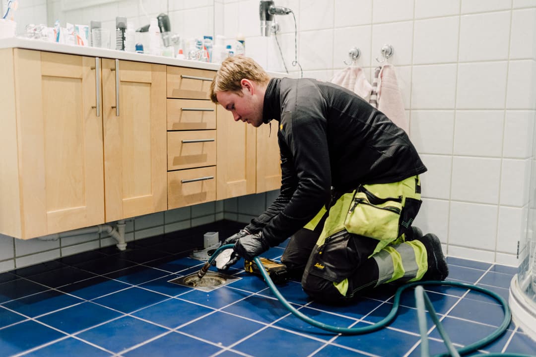 Bilde som viser spylebiloperatør fra Spylevakta som utfører spyling av avløpsrør via sluk på bad